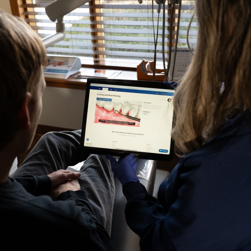 Two people looking at a screen that has a picture demonstrating dental cleaning