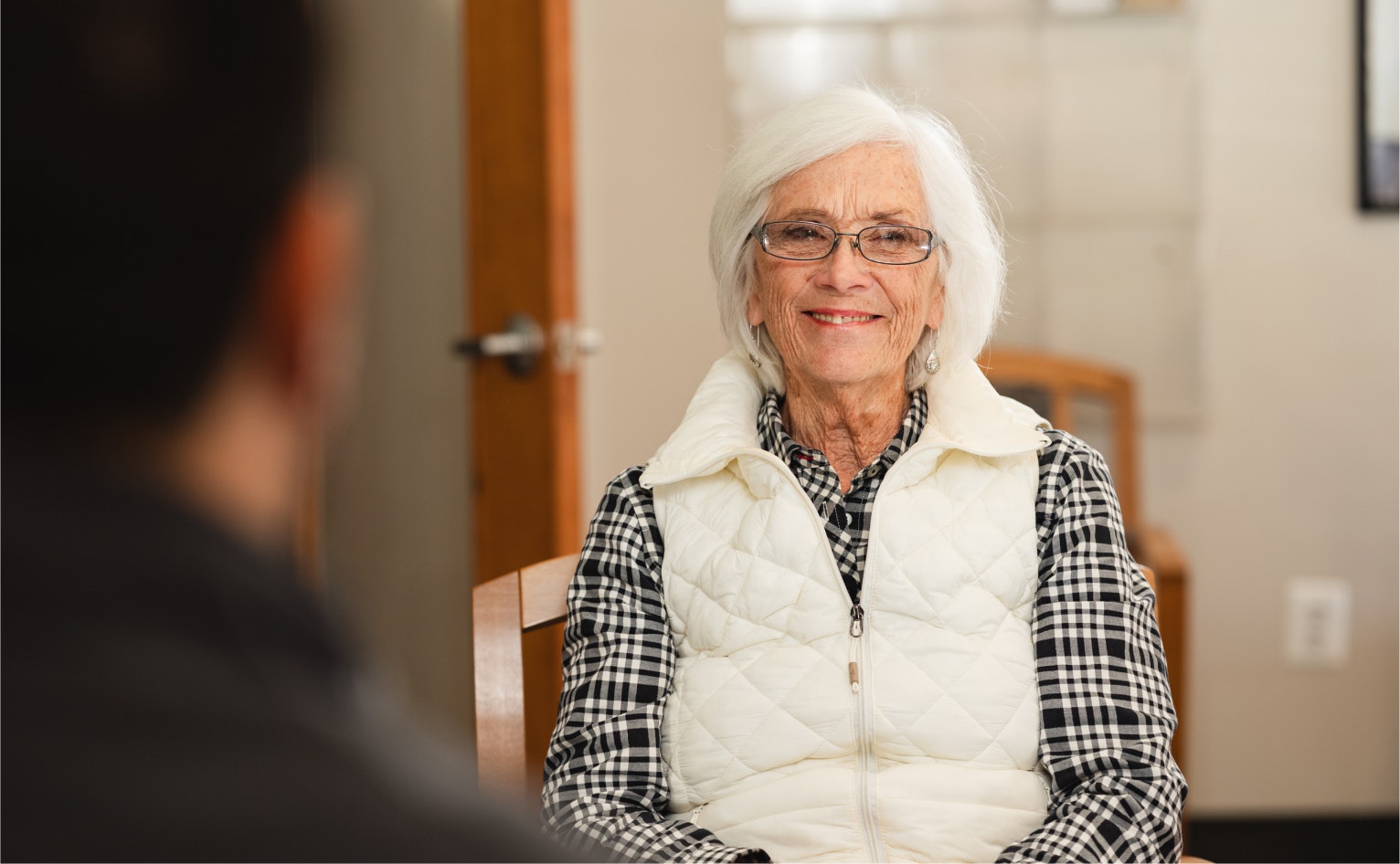 Older woman in a white vest talking to someone